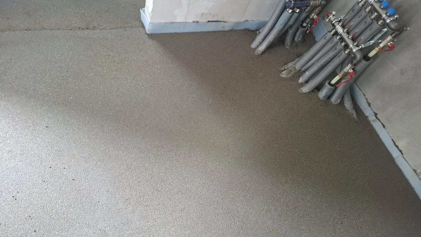 Floor screed next to an underfloor heating manifold
